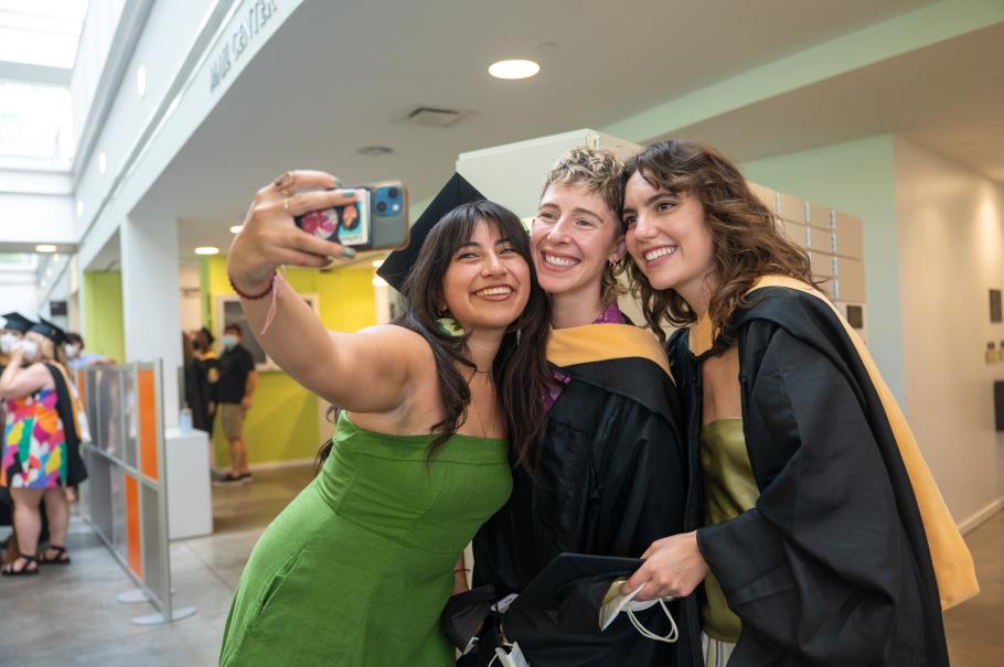 Three students pose for a selfie before commencement.