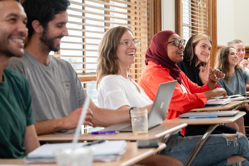 Students smile and listen to a classmate during a presentation.