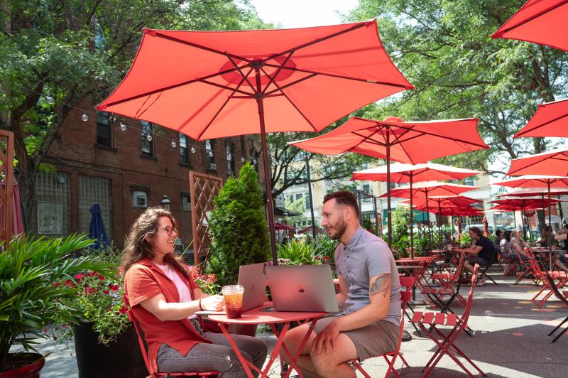 Two students sit outside working on their laptops at Summer on Strong in downtown Northampton