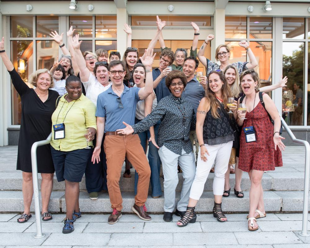 a group of 20 alums smiling, arms raised outside the Smith College Conference Center during the 2018 Centennial celebration