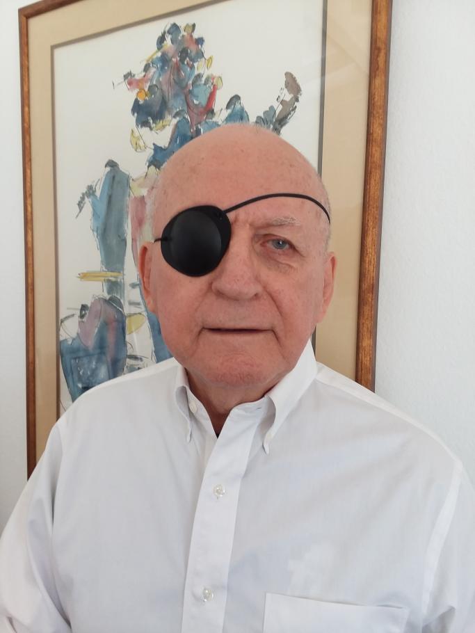 Glendon Geikie wears a white button up shirt and a black eye patch over one eye.