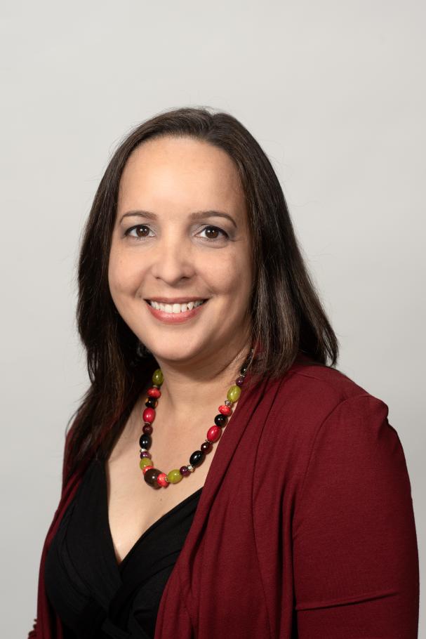 Yesselis Rosario smiles at the camera wearing a black top, maroon cardigan and beaded necklace.