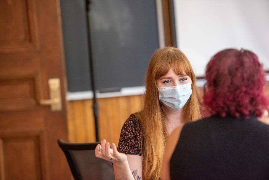 A student wearing a mask is engaged in conversation with another student. 