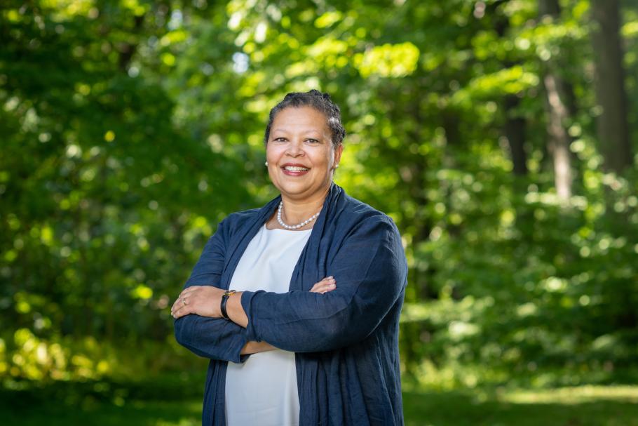 Portrait of incoming Smith College President Sarah Willie-LeBreton standing in front of green trees and wearing a blue top.