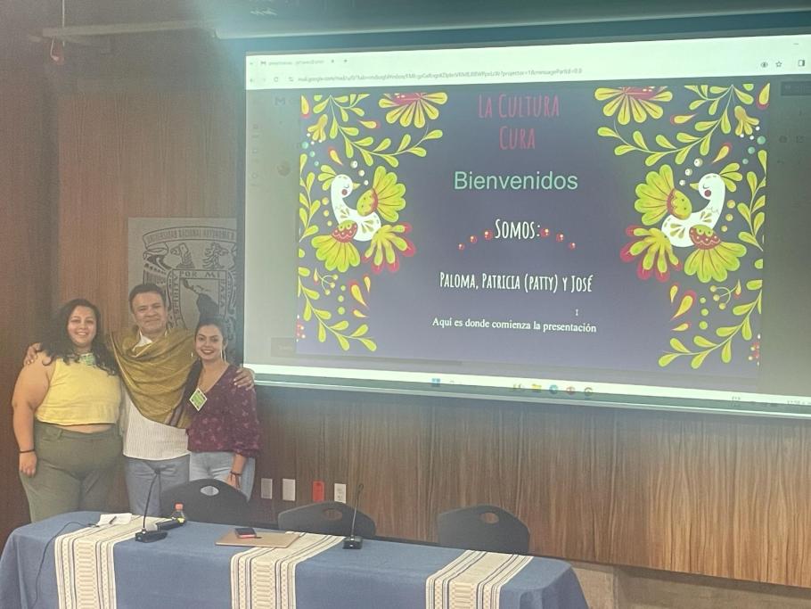 Three people stand next to a projection screen