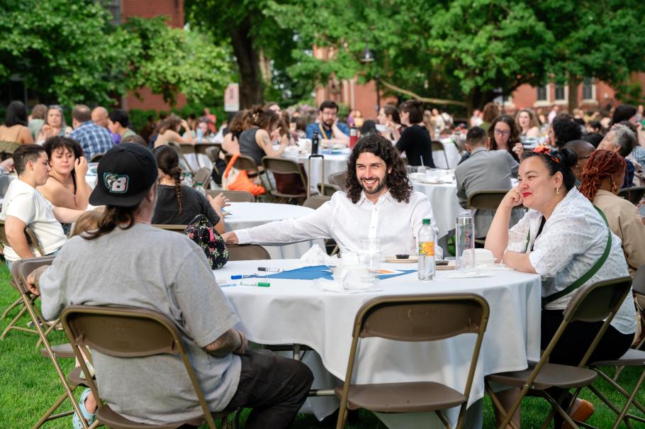 Crowd of attendees at the opening ceremony sitting at tables on Seelye Lawn