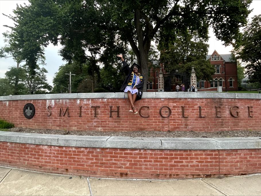 Gadria poses in her cap and gown on the Smith College entry wall. 