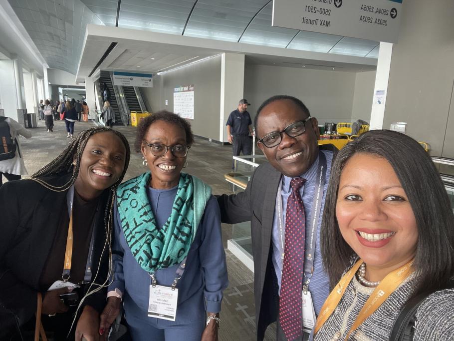 Four people take a selfie in a hallway. Hugo Kamya and Cheryl Aguilar on right