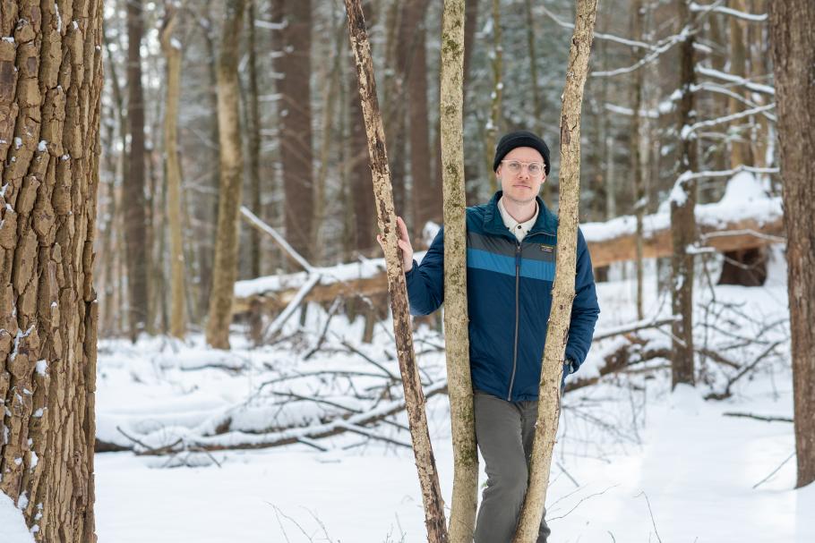 Kai Pratt poses for a photo in a snowy forest.