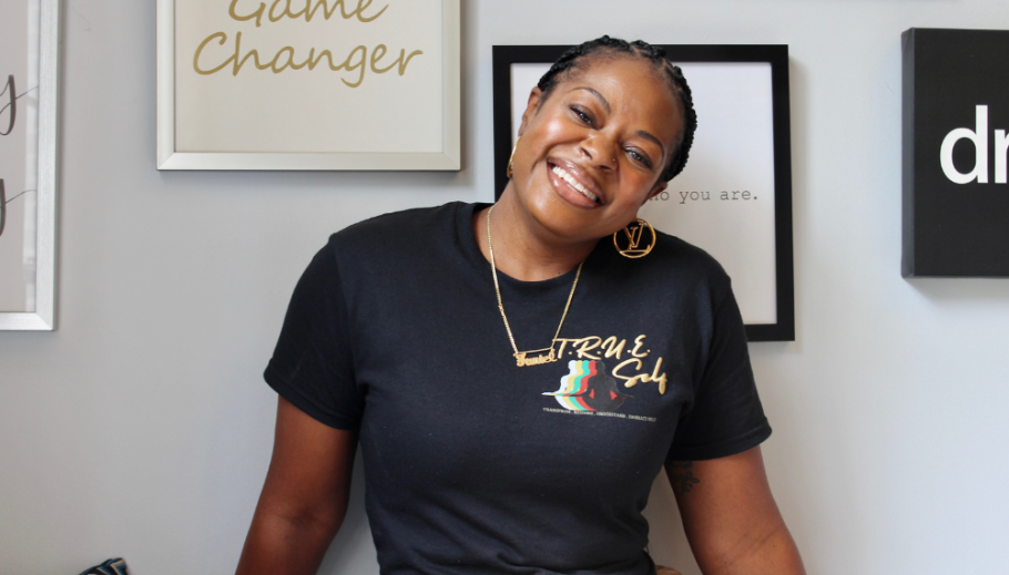 Nicole Faniel-Wilson wearing black tshirt smiling against grey wall with art hanging