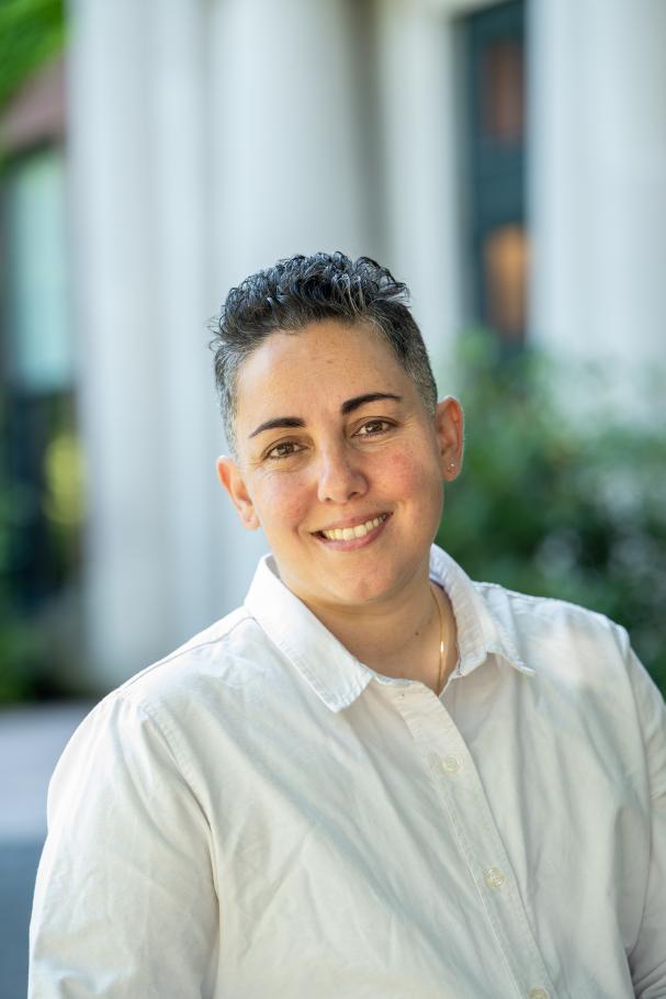Lev Fein wearing white button down smiling with white columns of a building in background