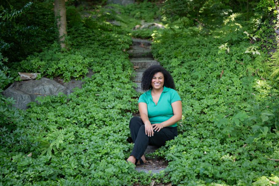 Alexis Minnis sits on a stone pathway among lush greenery