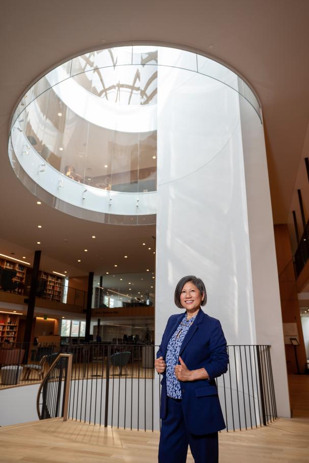 Marianne Yoshioka stands in front of a round skylight staircase in Neilson Library wearing a dark blue suit