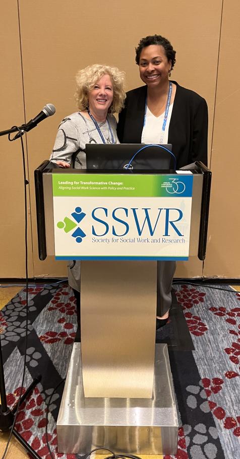 Marsha Kline Pruett and Brandyn McKinley stand together behind a podium with mic that reads SSWR