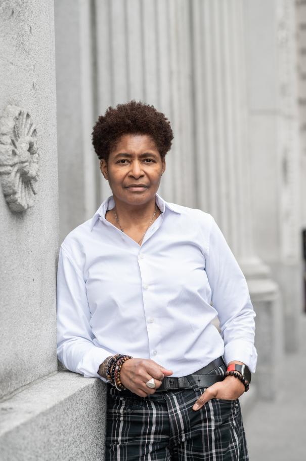 JD Fuller leans against a cement wall with ridged columns behind