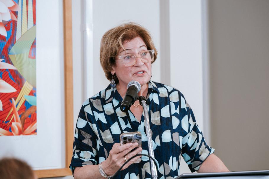 Laurie Peter stands at podium with mic speaking at 2025 Alumni Awards