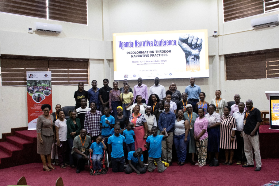 Group of about 30 practitioners under a banner that reads Uganda Narratives Conference. Hugo Kamya lower left, first kneeling in front row