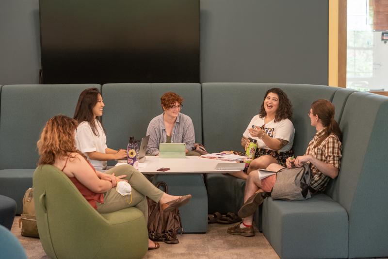 Five students sit on a curved banquette in Nielson Library. 