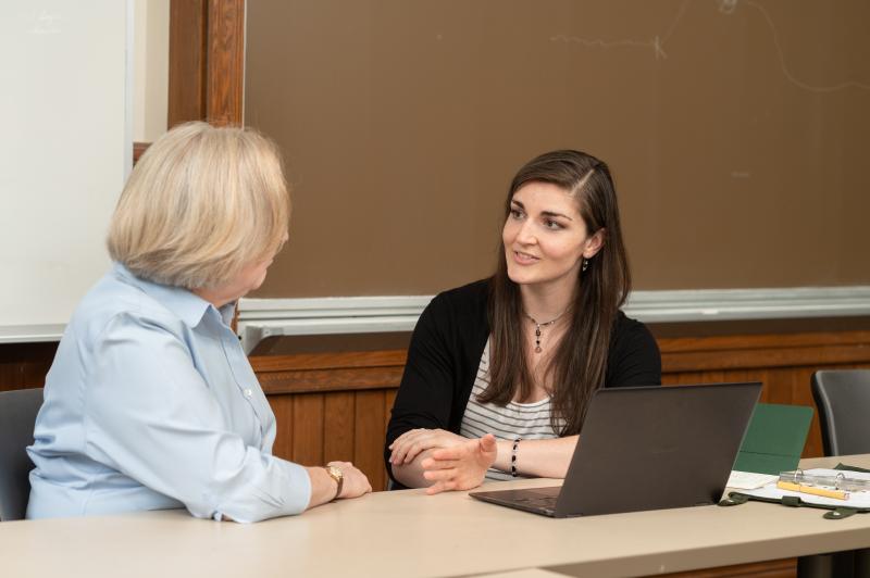 A student and faculty member engage in consultation in a classroom. 