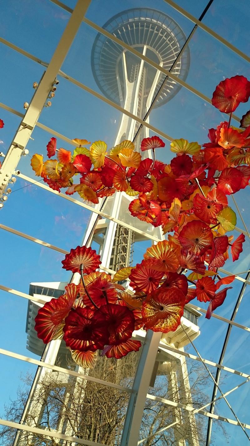 Photo of Seattle Space Needle taken from below with red and yellow flowers in foreground. 