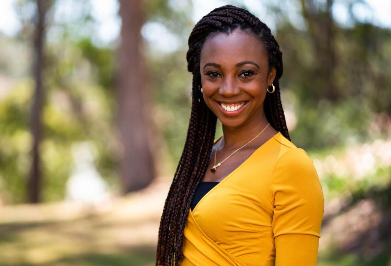 instructor danielle cottonham mason smiles outside in yellow