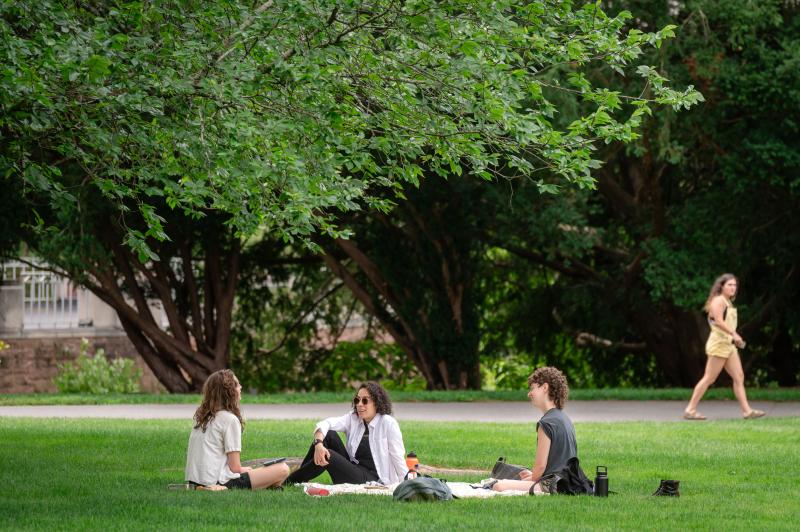 Three SSW students sit on the grass during the 2023 closing ceremony. 