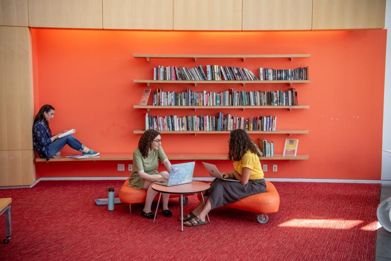 Three students sit in a lounge in the Campus Center studying. 