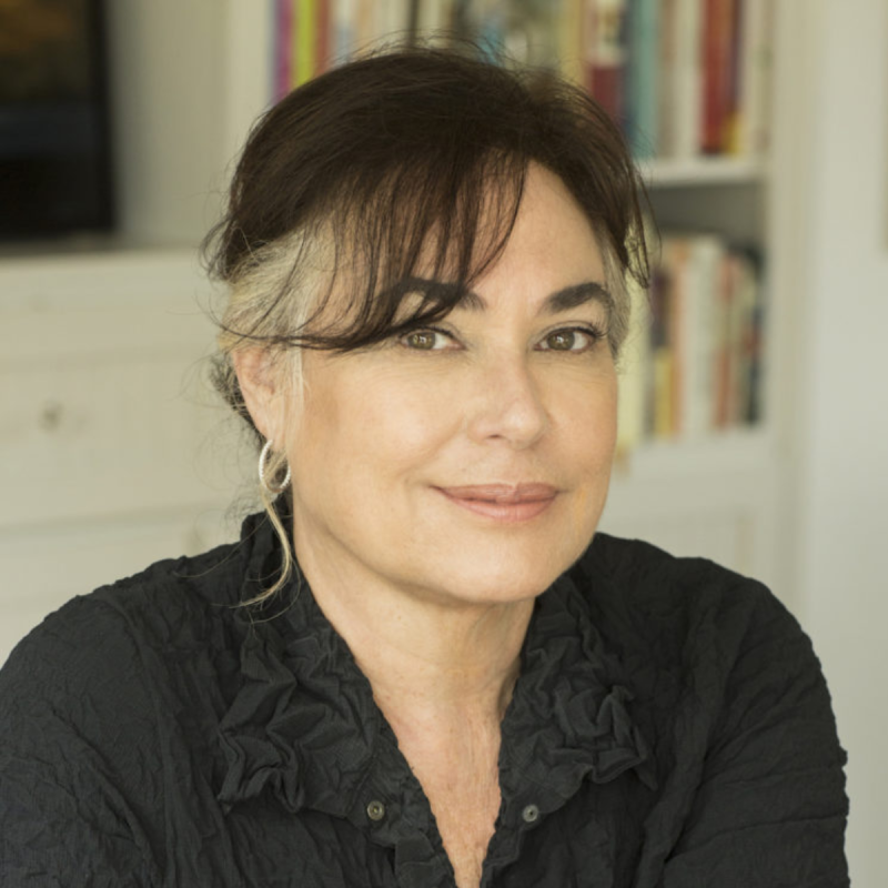 Amy Bloom wearing black shirt smiles with books behind