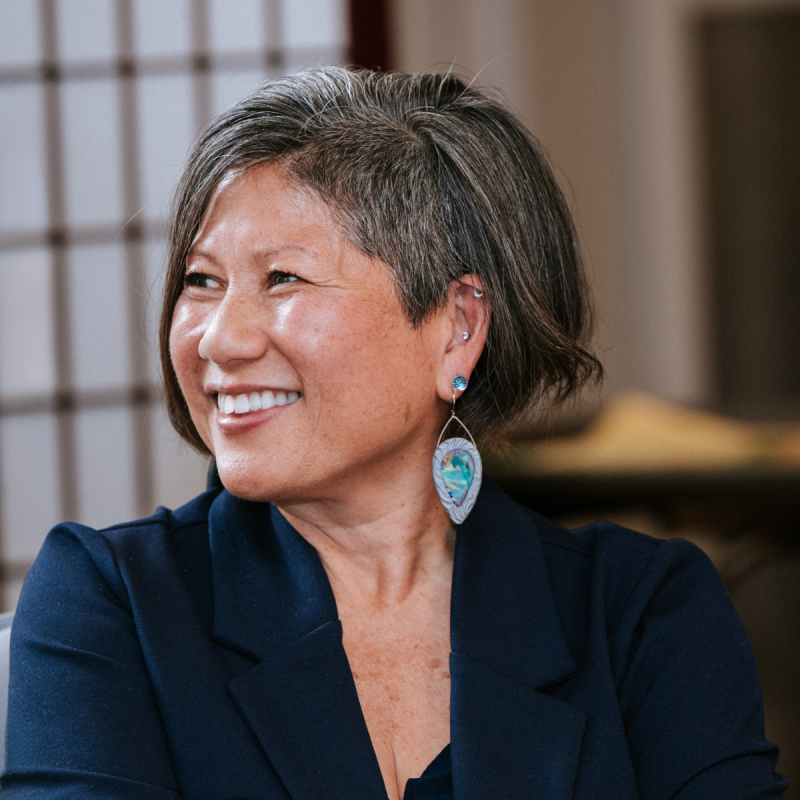 Marianne Yoshioka wearing blue blazer smiling and looking to the left