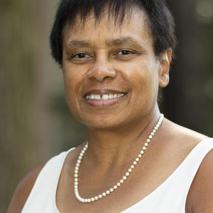 Portrait of Tanya Greathouse wearing a white tank top and a pearl necklace. 