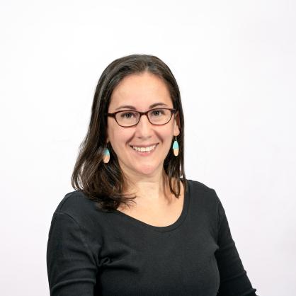 Madelyn Neely wears a black top and glasses and smiles at the camera.