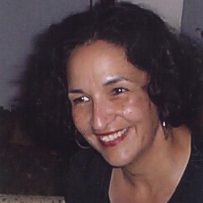 Lourdes Mattei smiles at the camera wearing a black top.