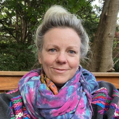 Shannon Sennott smiles at the camera while wearing a colorful pink and blue scarf.