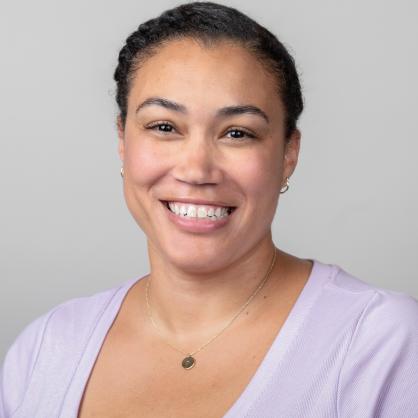 Makia Matheis portrait wearing lavender shirt against white wall
