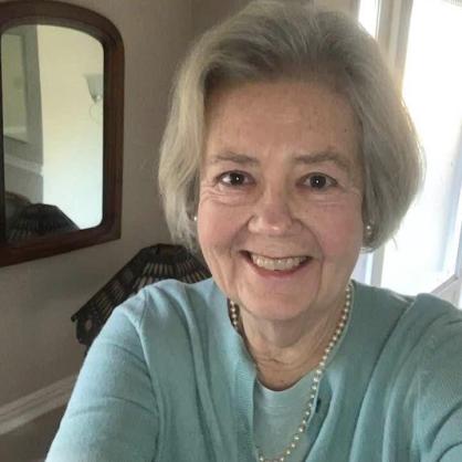 Debra Hull taking a selfie wearing turquoise sweater with mirror and wall behind