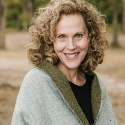 Jennifer Swanberg wearing a green wrap smiling outside with brown grass behind and trees