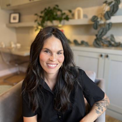 Devon Cozens sits in a chair with white cabinets behind