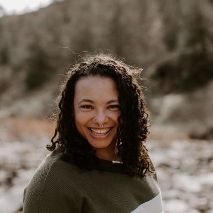 Rebecca Davis stands outside with rocks and trees behind