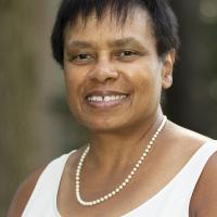 Portrait of Tanya Greathouse wearing a white tank top and a pearl necklace. 