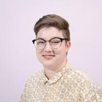 Max Ansorge smiles at the camera wearing a button down shirt and glasses.