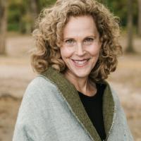 Jennifer Swanberg wearing a green wrap smiling outside with brown grass behind and trees