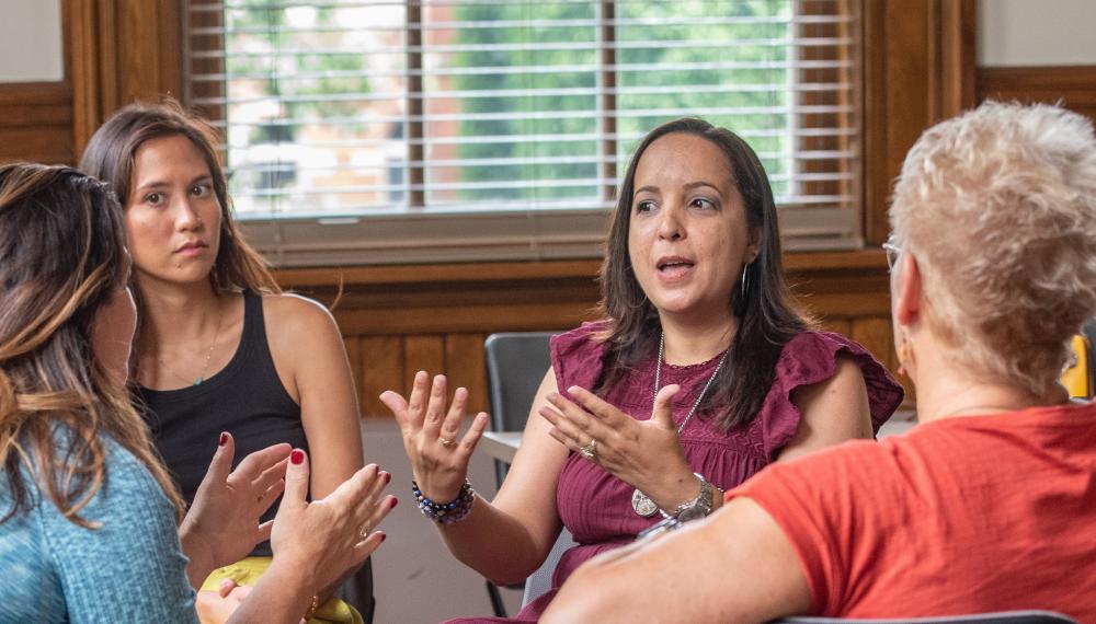 Yesselis Rosario talks with her hands to three other people.