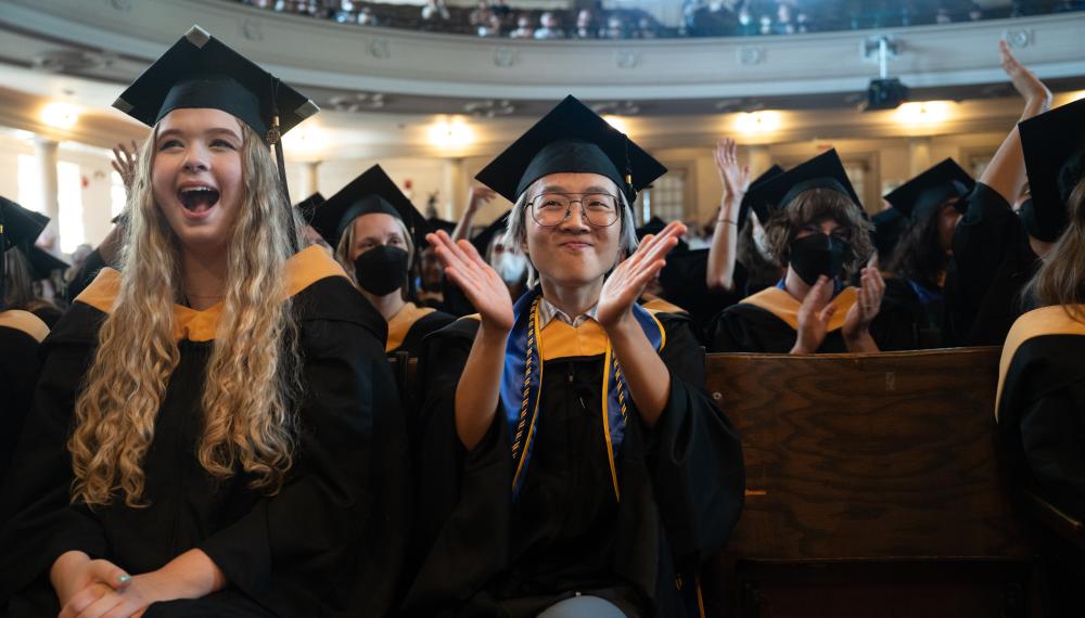 Students clap and cheer for a classmate while sitting in John M. Greene Hall during Commencement 2023.