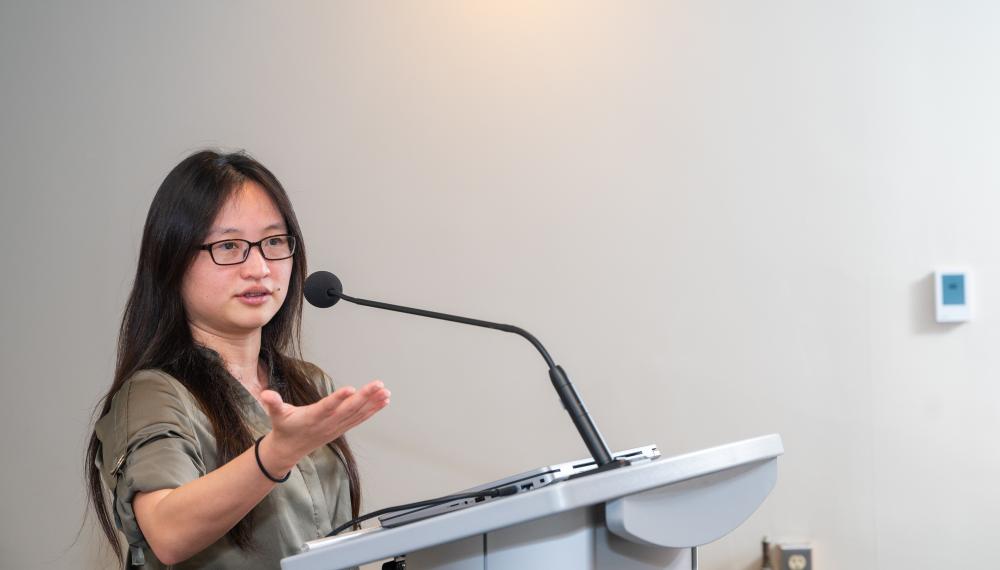 Helen Chao speaking behind a podium with mic