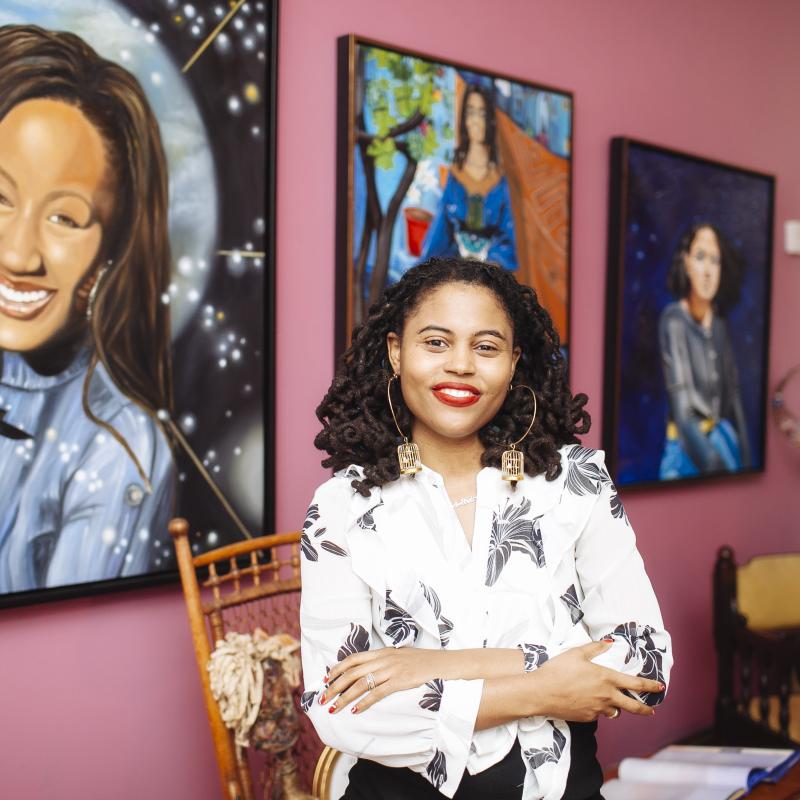 Loren Cahill stands in front of several paintings at the Colored Girls Museum in Philadelphia, Pennsylvania.
