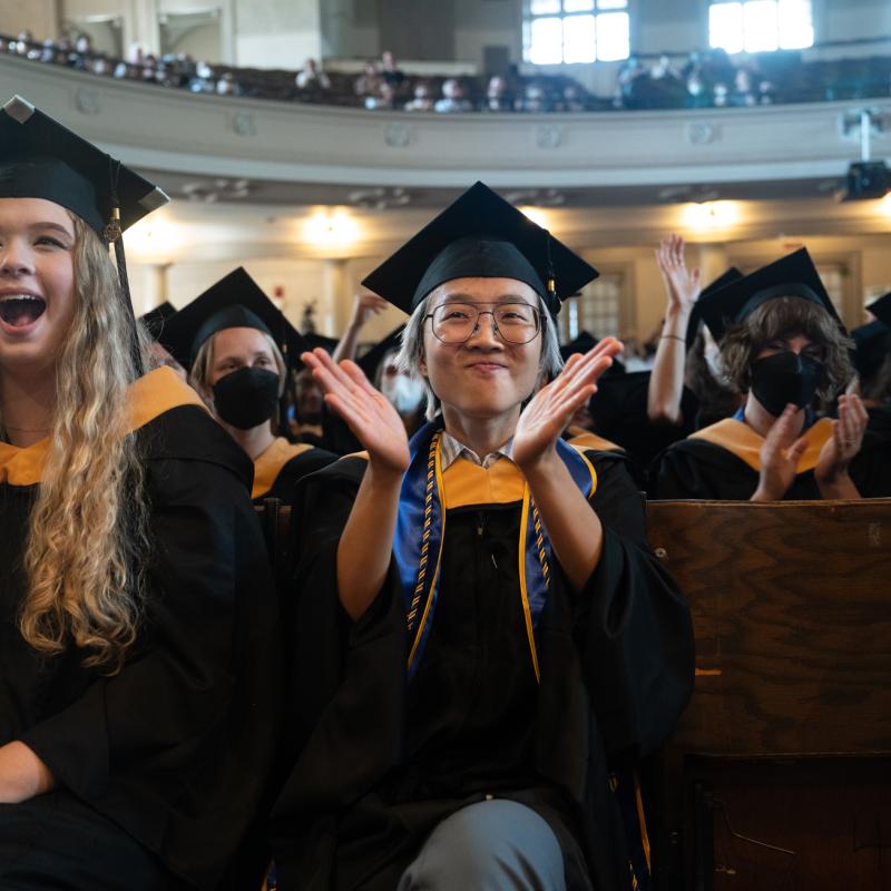 Students clap and cheer for a classmate while sitting in John M. Greene Hall during Commencement 2023. 