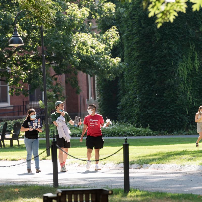 Three students walk on a paved walkway on the Smith College campus.