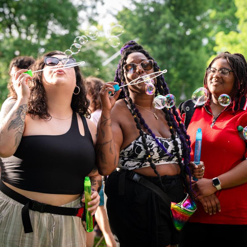 Three students blow bubbles on Seelye Lawn