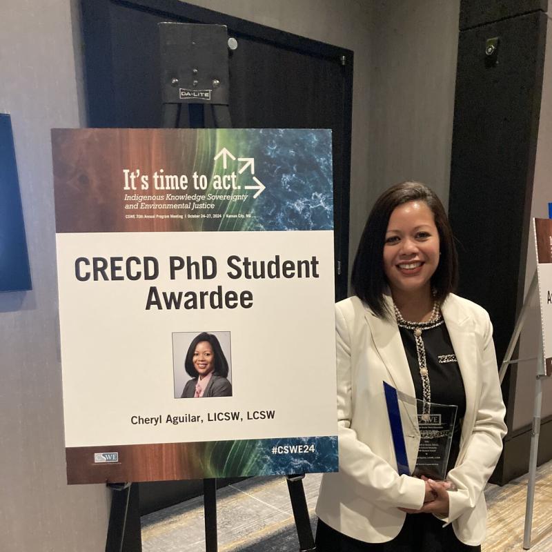 Cheryl Aguilar poses next to a poster announcing her award at CSWE