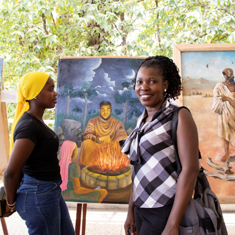 Student and Fidelis Nabukenya (r) at Uganda Narratives Conference with art behind- organized by Hugo Kamya